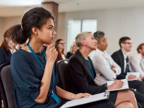 Audience sitting in a row while listening to presentation at conference hall